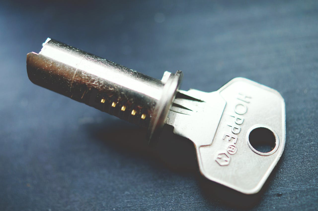 about-us-01 Detailed close-up image of a metallic key with lock cylinder on a dark surface, highlighting intricate details.